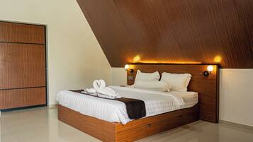 Un dormitorio con techo inclinado, estructura de cama de madera, colchón blanco y aire acondicionado instalado en la pared.