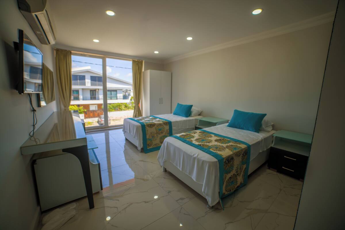 Une chambre d’hôtel avec deux lits, un bureau et une vue sur un bâtiment à l’extérieur.