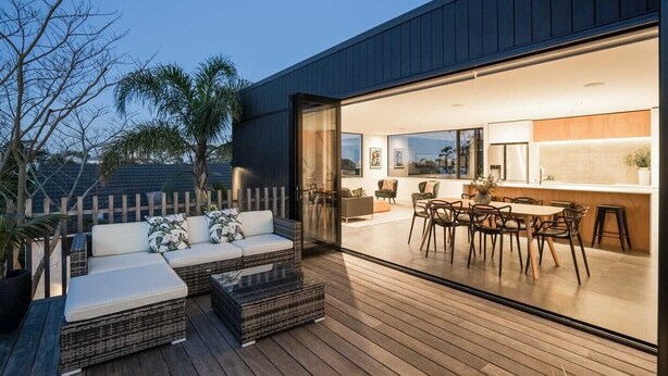 An outdoor deck with a sofa and dining area, connected to a modern kitchen with large windows. - Birkenhead Point Beauty - quiet family home with amazing views. (Auckland)