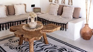 A cozy living room with a rattan chandelier, a woven macrame wall hanging, a sofa with cushions, a coffee table, and a vase with dried plants. - the macan Bingin (Pecatu)