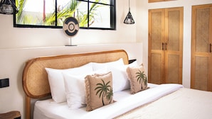A bed with a woven headboard, white bedding, and two palm tree pillows. - the macan Bingin (Pecatu)