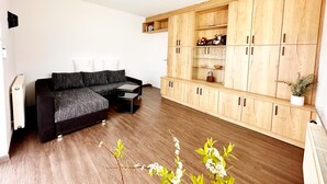 Ein modernes Wohnzimmer mit einer Eckcouch, Holzsäcken und einer eingebauten Regaleinheit.