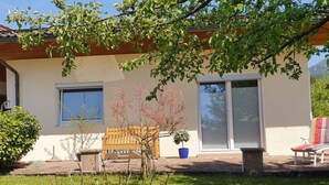 Ein Haus mit Terrasse, einer Holzbank und einem Blumentopf.