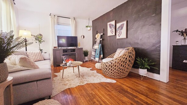 A living room with a TV, sofa, wicker chair, and a fireplace.