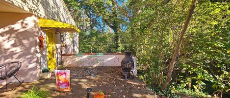 A rustic outdoor area with a wooden structure, a welcome sign, a chair, and a potted plant.