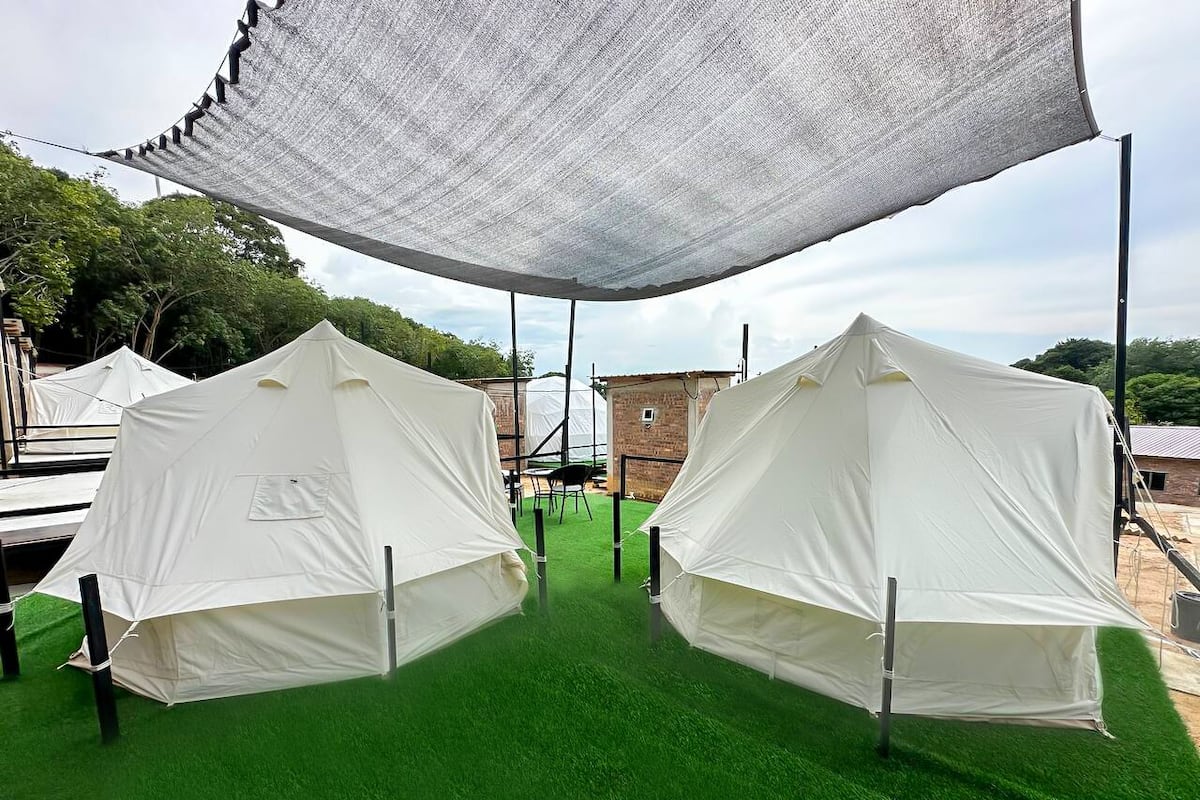 Two white tents on artificial green turf under a large white canopy.