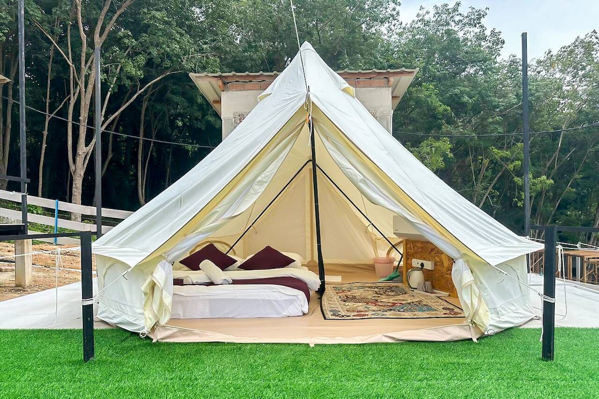 A tent with a bed inside, surrounded by artificial grass.