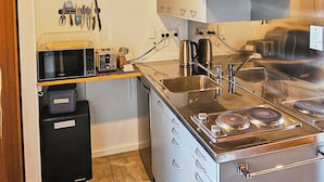 Eine kleine Küche mit Mikrowelle, Toaster, Wasserkocher und Edelstahlgeräten.