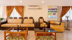 A modern living room with a sofa, two armchairs, a coffee table, and a reception desk. -  Treebo Classic Highway Side (Thiruvananthapuram)