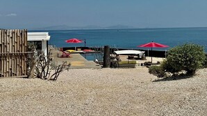 Zona de playa con piscina, sombrillas rojas y vista al mar.