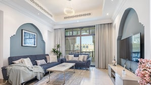 A modern living room with two sofas, a coffee table, and a TV on a stand. - Tajer Residence Old Town Island 5038 Downtown (Dubai)