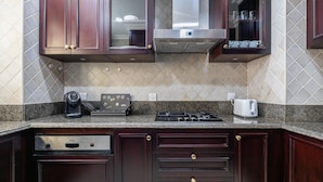 A kitchen with dark wood cabinets, a built-in stove, a coffee maker, and a toaster. - Tajer Residence Old Town Island 5038 Downtown (Dubai)