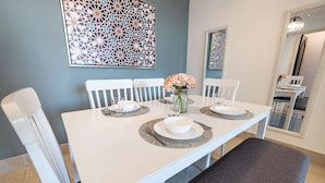 A dining area with a white table set for four, surrounded by white chairs. - Tajer Residence Old Town Island 5038 Downtown (Dubai)