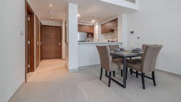Une cuisine moderne avec des meubles en bois, un îlot central et un coin repas comprenant une table et des chaises.