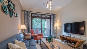 A living room with a blue sofa, a red armchair, a wooden coffee table, and a TV on a wooden stand. - Yansoon 4 207 Downtown (Dubai)