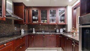 A modern kitchen with dark wooden cabinets, a granite countertop, and a stainless steel refrigerator. - Yansoon 4 207 Downtown (Dubai)