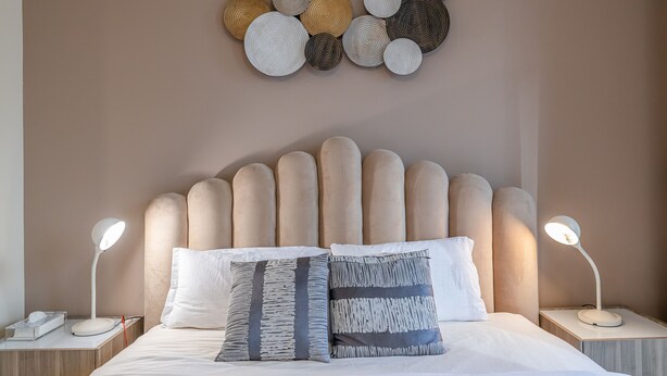 A neatly made bed with two pillows, a bedside lamp, and a wall art piece above. - Yansoon 4 207 Downtown (Dubai)