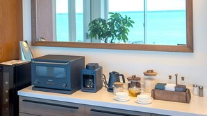 Una cocina con cafetera, hervidor y vista al mar.