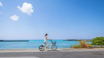 Iemand fietst op een weg met uitzicht op de oceaan en een heldere lucht.