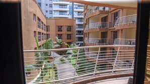 Uitzicht op een meerlaags woongebouw met balkons, een patio met palmbomen en een betegelde vloer.