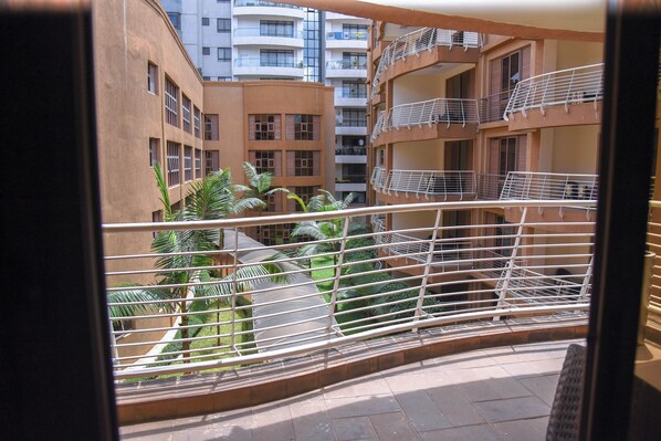 A view of a multi-story residential building with balconies, a courtyard with palm trees, and a tiled floor.