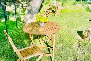 Sit and unwind in a serene garden setting with a round table and comfortable chairs.