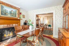 Cozy dining area with a traditional fireplace, wooden dining table, and comfortable seating.