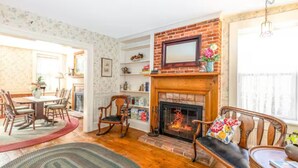 A cozy living room with a fireplace, wooden furniture, and a bookshelf. - Briarstone Inn | Historic 7-Room Inn w/ Private Baths | Walk to Downtown Galena (Galena)
