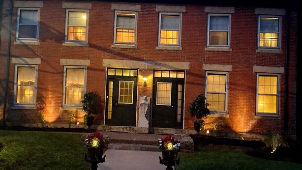 A brick building with a central entrance, multiple windows, and a statue in front. - Briarstone Inn | Historic 7-Room Inn w/ Private Baths | Walk to Downtown Galena (Galena)