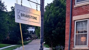 A sign for Briarstone Inn with a landscaped garden featuring rocks and grass. - Briarstone Inn | Historic 7-Room Inn w/ Private Baths | Walk to Downtown Galena (Galena)