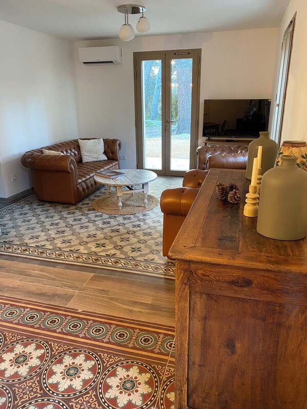 Ein Wohnzimmer mit braunem Ledersofa, einem Couchtisch und einer Holzkommode mit Kerzen.