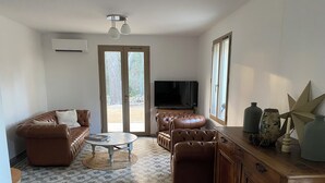 Un salon avec un canapé en cuir marron, une table basse ronde et un téléviseur.