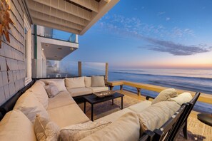 A modern outdoor living area with a sofa set, a coffee table, and a view of the ocean.