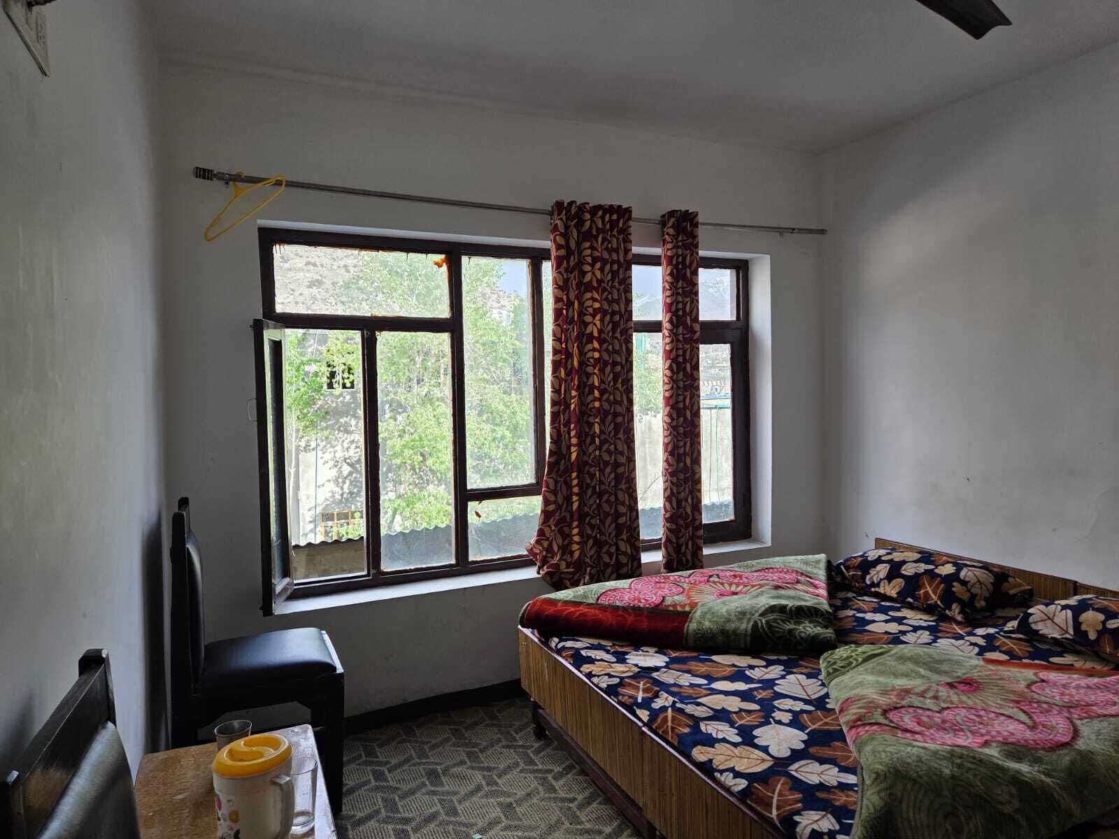A room with a bed, a window, a radiator, and a table with a cup and saucer.