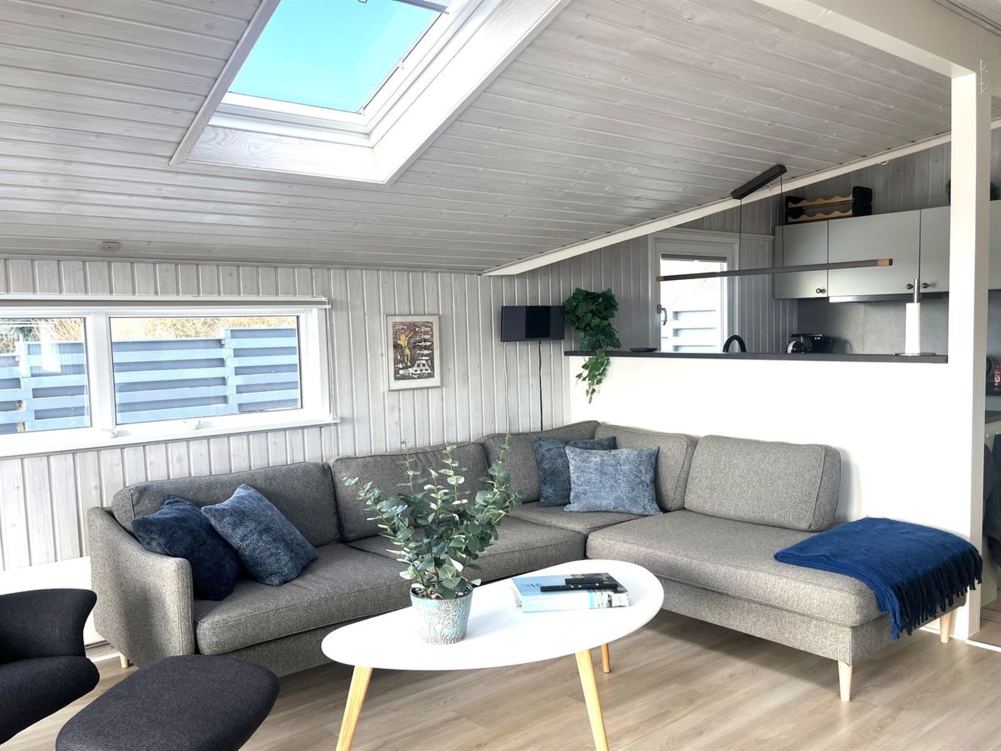 A modern living room with a sofa, coffee table, and a skylight.