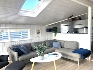 A modern living room with a sofa, coffee table, and a skylight.