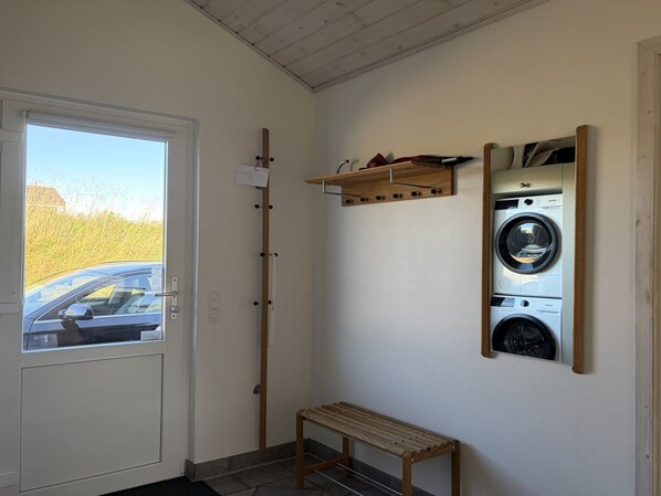 A laundry area with a washing machine, a drying rack, and a bench.