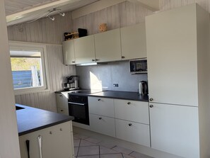 A kitchen with white cabinets, a black countertop, and a window.