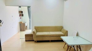 A minimalist room with a beige sofa, a small white table, and a glass partition. - Era Apartment Chua Ha (Hanoi)