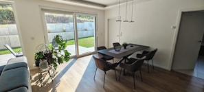 A dining area with a table and chairs, a potted plant, and a view of a grassy yard through a sliding glass door. - Modern work and relaxation paradise (Contwig)