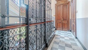 Ein Korridor mit Schachbrettfußboden, einem Metallgitter und Holztüren.