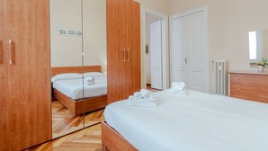 Ein Schlafzimmer mit Holzschrank, Bett mit weißen Leinen und einem Spiegel.
