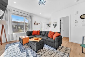 A modern living room with a sectional sofa, ottoman, and patterned rug. - Cozy Rustic House(pet friendly/garage/backyard) (Beaumont)