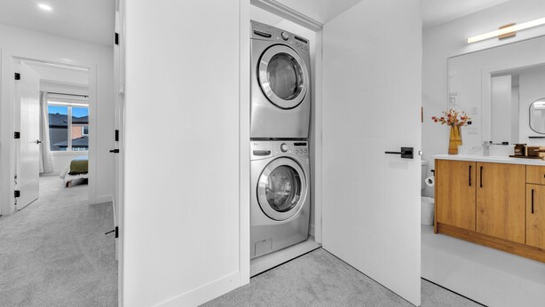 A modern laundry room with two stacked washing machines, a wooden cabinet, and a mirror. - Cozy Rustic House(pet friendly/garage/backyard) (Beaumont)