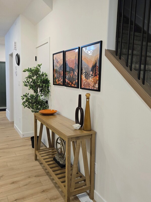 A hallway with a wooden console table, a potted plant, and three framed pictures on the wall. - Cozy Rustic House(pet friendly/garage/backyard) (Beaumont)
