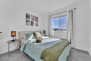 A bedroom with a bed, a nightstand, a window with curtains, and wall art. - Cozy Rustic House(pet friendly/garage/backyard) (Beaumont)