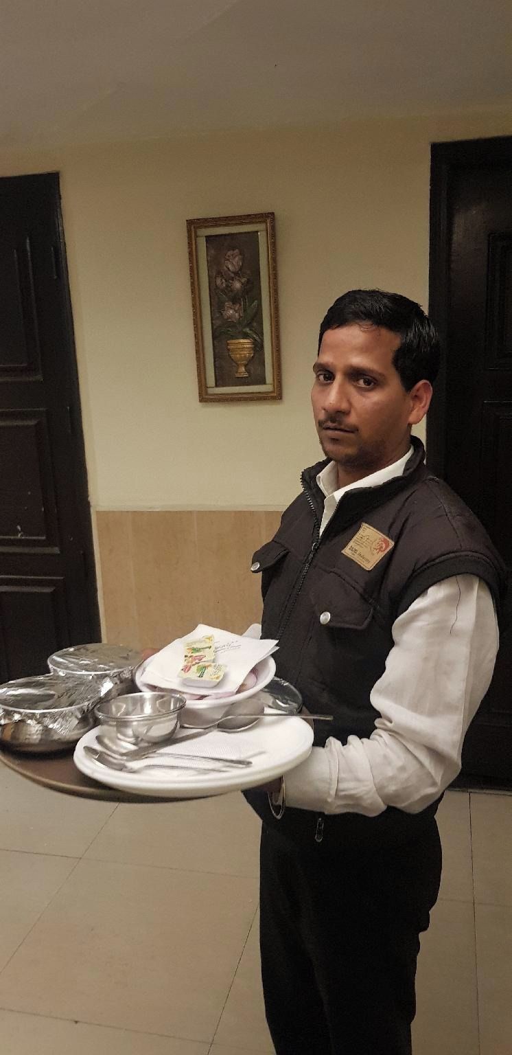 A person holding a tray with plates, bowls, and utensils, likely serving food.