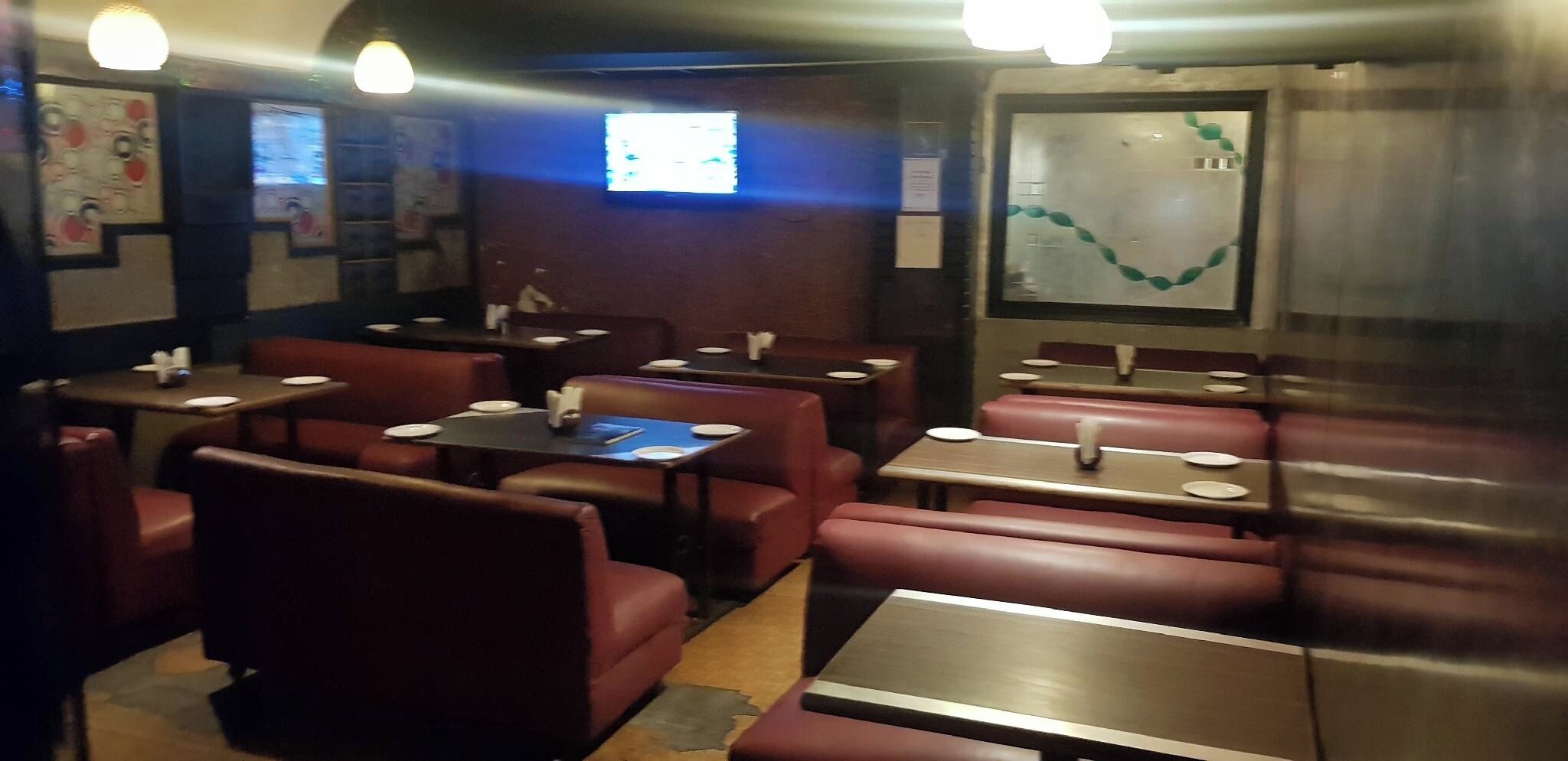 A restaurant interior with booths and tables, some with plates and cutlery.