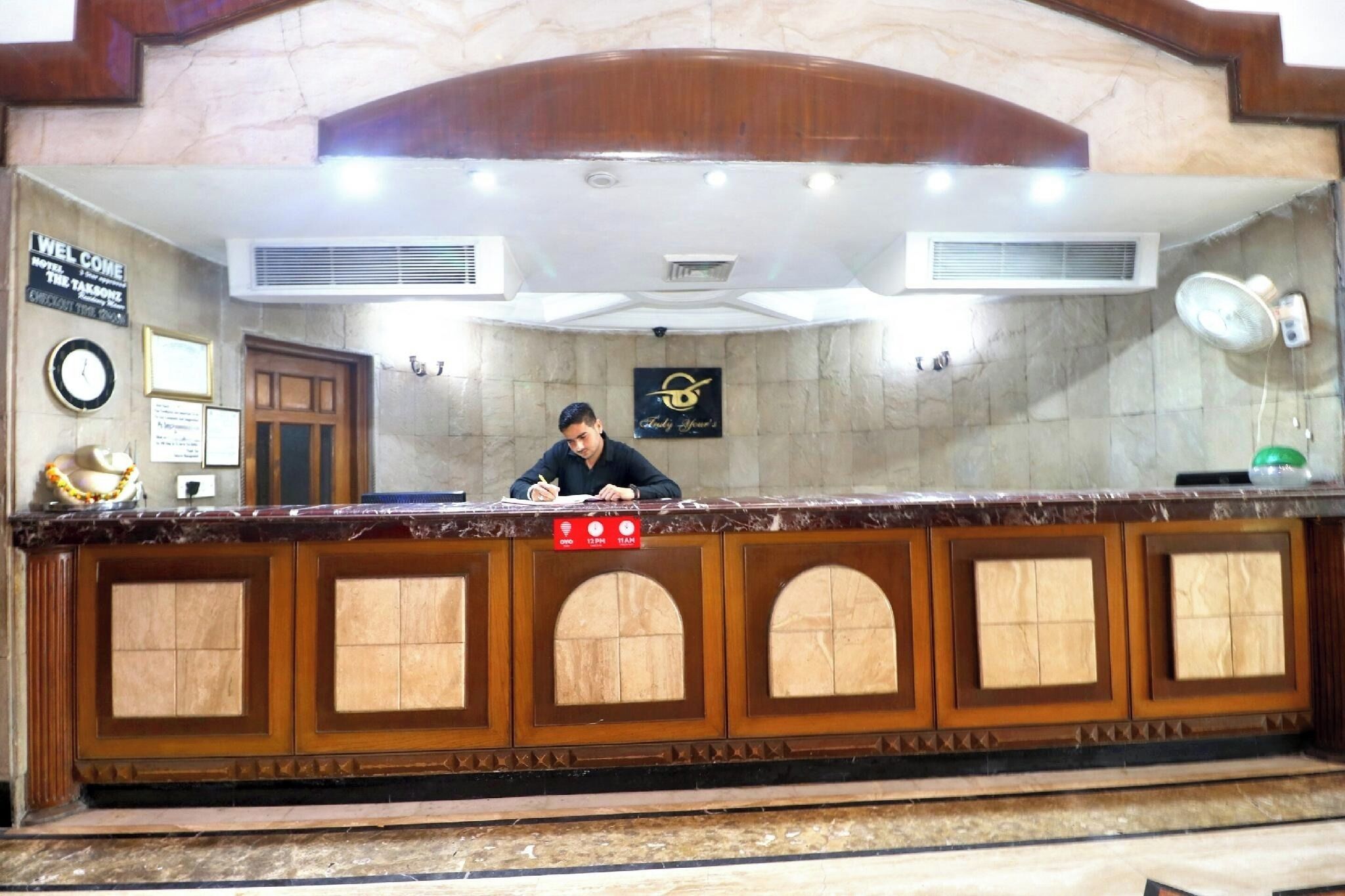 A reception desk with a clock, a sign reading "Welcome", and a logo on the wall.