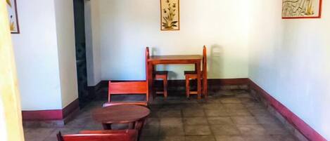 Una habitación con una mesa y sillas de madera, un banco y una puerta.